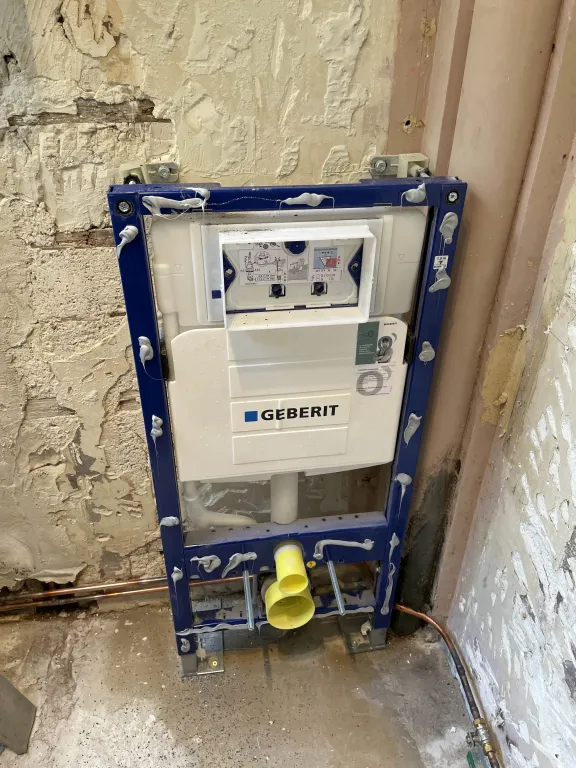 Installation du châssis bâti-support Geberit pour WC suspendu et raccordements de plomberie sur mur brut