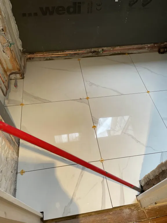 Pose de carrelage effet marbre chez le client. Le travail est propre et joints soignés.